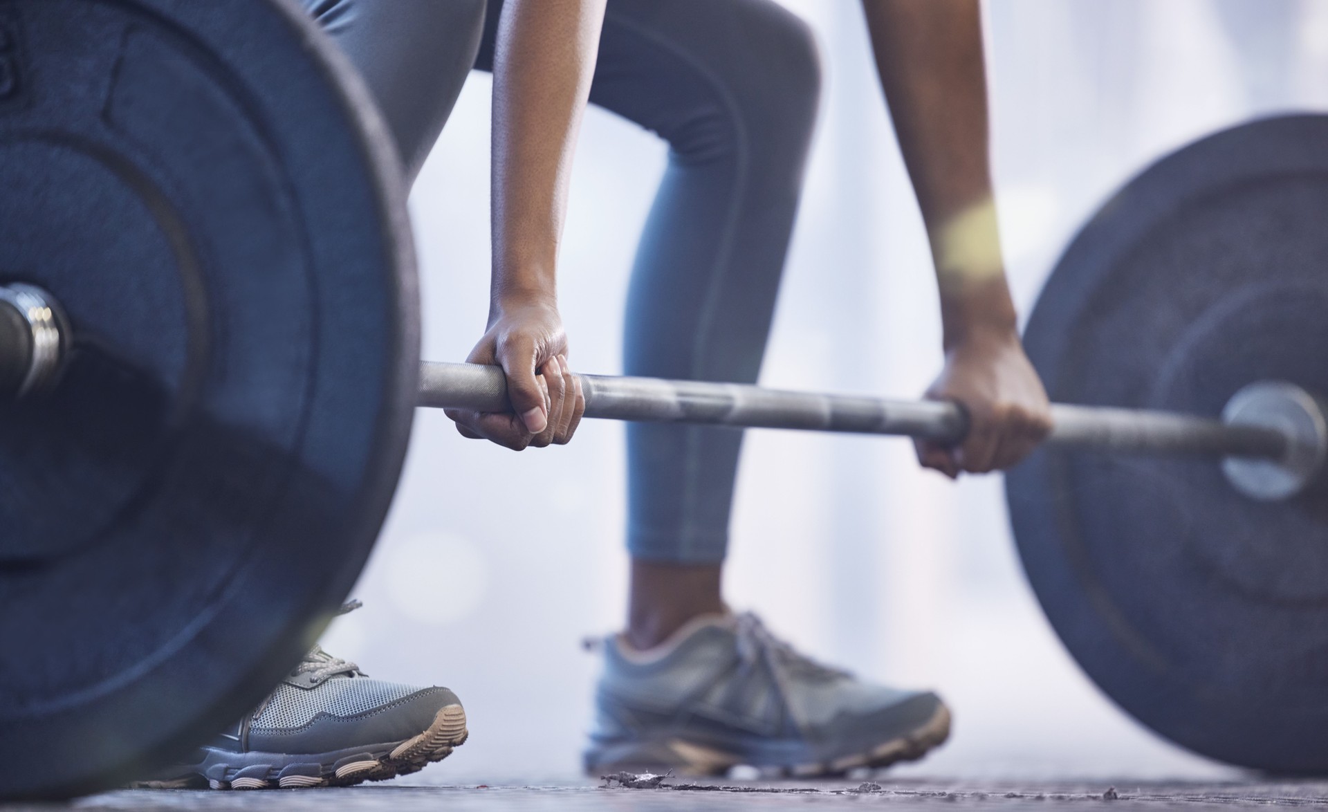 Closeup shot of an unrecognisable woman exercising with a barbell in a gym